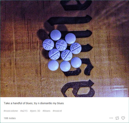 A close-up of a wooden surface with a bunch of small white pills scattered on it. The pills are arranged in a scattered manner with some overlapping each other. The background is a light brown color and there are a few black objects scattered around the pills. The text on the image reads "Take a handful of blues try n dismantle my blues".