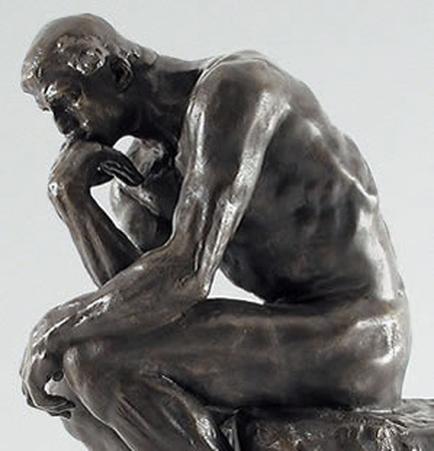 A sculpture of a man sitting on a rock. The sculpture is made of bronze and appears to be highly detailed with the man's body and facial features clearly visible. He is sitting with his left hand resting on his chin and his right hand on his knee as if deep in thought. His head is tilted downwards and his eyes are closed suggesting that he is in a contemplative state. His posture is relaxed and his body is slightly hunched over with his head slightly tilted downwards. The background is plain and white making the sculpture the focal point of the image.