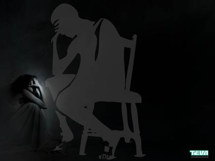 A black and white photograph of a silhouette of a man sitting on a chair. The man is facing away from the camera with his head in his hands and his body slightly hunched over. He appears to be deep in thought. On the left side of the image there is a woman sitting on the floor with her head resting on her hand. She is wearing a long flowing dress and her hair is pulled back in a bun. The background is completely black making the silhouette stand out even more. The image conveys a sense of loneliness and despair.