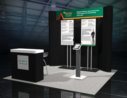 A trade show booth with a black background and a green and red logo on the top left corner. The booth has a white counter on the left side with the word "tea" written on it. On the right side of the booth there is a large screen with information about the company's products and services. The screen displays a picture of a man in a suit and tie and there are two smaller screens on either side of it. The floor is made of black tiles and the booth is set up in a large warehouse-like space with high ceilings and large windows.