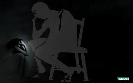 A black and white photograph of a silhouette of a man sitting on a chair. The man is facing away from the camera with his head in his hands and his body slightly hunched over. He appears to be deep in thought. On the left side of the image there is a woman sitting on the floor with her head resting on her hand. She is wearing a long flowing dress and her hair is pulled back in a bun. The background is completely black making the silhouette stand out even more. The image conveys a sense of loneliness and despair.
