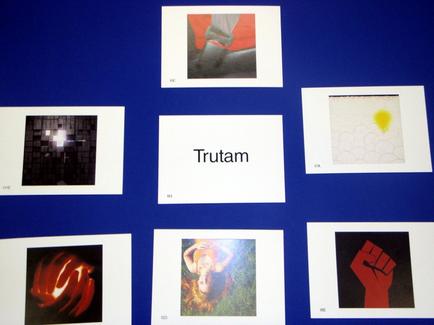 A collage of six square photographs arranged in a grid-like pattern on a blue background. Each photograph is a different color and has a unique design. The first photograph on the top left is a black and white photograph of a person's face with their eyes closed and their mouth slightly open. The second photograph in the top center is a close-up of a red and black abstract background with a white square in the middle. The third photograph is in the center of the image with the word "Trutam" written in white text above it. The fourth photograph is on the right side of the collage and is a square with a yellow circle in the bottom right corner. The fifth photograph is at the bottom left corner and is of a hand with red flames on it. Overall the image appears to be a collection of photographs related to the concept of trutam.