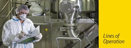 A person wearing a white protective suit a face mask and a head cap working in a factory. The person is holding a clipboard and appears to be writing on it. In the background there is a large stainless steel machine with pipes and valves. The machine is likely used for processing or processing food or other industrial purposes. The image is accompanied by text that reads "Lines of Operation".