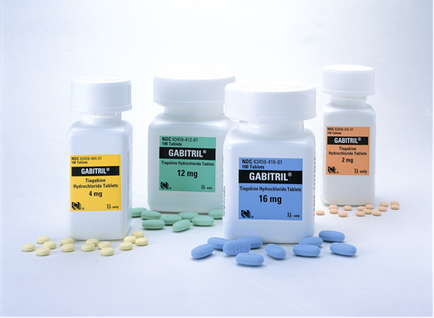 Four white plastic bottles with white caps arranged in a row on a white background. Each bottle has a label on it that reads "GABITRIL" in bold black letters. The label also has the number "12 mg" and "16 mg" written in smaller black letters indicating that the bottles contain 12 mg of the medication. There are also a few small blue and green pills scattered around the bottles. The bottles appear to be new and unused.