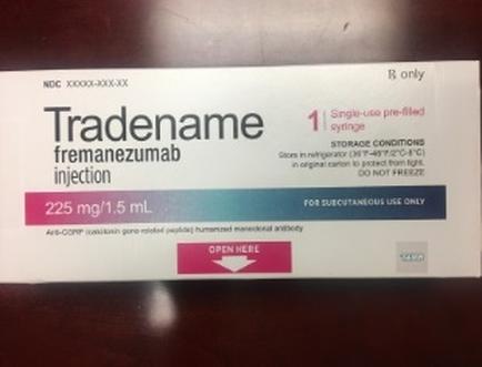 A photograph of a box of Tradename fremanezumab injection. The box is rectangular in shape and has a white background. The front of the box has the brand name "Trademename" written in bold black letters at the top followed by the product name "Fremanezumab" in smaller black letters. Below that there is a description of the injection which states that it is 225 mg/1.5 ml in size and is for subcutaneous use only. The box also has a label that reads "1 Single-use pre-filled syringe" and "Storage conditions" in blue letters. The label also mentions that the injection is not available for purchase. There is an "Open Here" button at the bottom right corner indicating that the box is open and ready to be used.