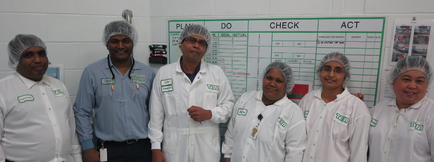 A group of six people standing in front of a whiteboard with a list of tasks written on it. The tasks are written in black text and are arranged in a grid-like format. There are six people in the group six men and three women all wearing white lab coats and hairnets on their heads. They are all smiling and appear to be posing for the photo. The man on the left is wearing a blue shirt and a stethoscope around his neck while the man in the center is holding a clipboard. The other six people are wearing white shirts with green labels on them. The background of the image is a white wall with a bulletin board and a poster on the right side.