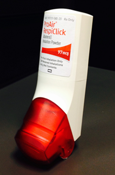 A white-colored device with a red-colored cap. The device is labeled "ProAir RespiClick" and has a label that reads "97 mg". The device appears to be an inhaler as indicated by the label. The cap is slightly tilted to the side and it is resting on a black surface. The background is also black making the device stand out.