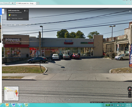 A street view of a popeye store on the corner of a street. The store is a two-story building with a red awning and a sign that reads "popeye". There are several cars parked in front of the store and a few people walking on the sidewalk. The street is empty and there are no people visible in the image. The sky is blue and the weather appears to be sunny. There are power lines running across the street and a traffic light on the right side of the image is visible.