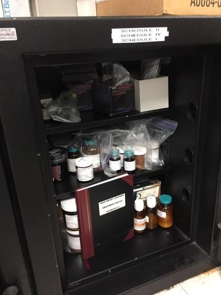 A black metal cabinet with three shelves. On the top shelf there are several small bottles of different sizes and colors including white blue and brown. The bottles are arranged neatly in the shelves with some of them spilling out onto the floor. In the center of the cabinet there is a red folder with a label that reads "Schedule 1 Schedule 2 Schedule 3 Schedule 4 Schedule 5 Schedule 6 Schedule 7 Schedule 8 Schedule 9 Schedule 10 Schedule 11 Schedule 12 Schedule 13 Schedule 14 Schedule 15 Schedule 16 Schedule 17 Schedule 18 Schedule 19 Schedule 20 Schedule 21 Schedule 22 Schedule 23 Schedule 24 Schedule 25 Schedule 26 Schedule 27 Schedule 28 Schedule 29 Schedule 30 Schedule 31 Schedule 32 Schedule 33 Schedule 34 Schedule 35 Schedule 36 Schedule 37 Schedule 38 Schedule 39 Schedule 40 Schedule 41 Schedule 42 Schedule 43 Schedule 44 Schedule 45 Schedule 46 Schedule 47 Schedule 48 Schedule 49 Schedule 50 Schedule 51 Schedule 52 Schedule 53 Schedule 54 Schedule 55 Schedule 56 Schedule 57 Schedule 58 Schedule 59 Schedule 60 Schedule 61 Schedule 62 Schedule 63 Schedule 64 Schedule 65 Schedule 66 Schedule 67 Schedule 68 Schedule 69 Schedule 70 Schedule 71 Schedule 72 Schedule 73 Schedule 74 Schedule 75 Schedule 76 Schedule 77 Schedule 78 Schedule 79 Schedule 80 Schedule 81 Schedule 82 Schedule 83 Schedule 84 Schedule 85 Schedule 86 Schedule 87 Schedule 88 Schedule 89 Schedule 90 Schedule 91 Schedule 92 Schedule 93 Schedule 94 Schedule 95 Schedule 96 Schedule 97 Schedule 98 Schedule 99 Schedule 100 Schedule 110 Schedule 115 Schedule 116 Schedule 117 Schedule 118 Schedule 119 Schedule 120 Schedule 121 Schedule 122 Schedule 123 Schedule 126 Schedule 127 Schedule 129 Schedule 130 Schedule 140 Schedule 135 Schedule 150 Schedule 151 Schedule 152 Schedule 153 Schedule 154 Schedule 156 Schedule 170 Schedule 175 Schedule 176 Schedule 177 Schedule 178 Schedule 179 Schedule 190 Schedule 181 Schedule 191 Schedule 192 Schedule 183 Schedule 191 schedule 192 Schedule 192 schedule 219 Schedule 219 Schedule 230 Schedule 220 Schedule 230 schedule.