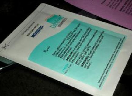 A piece of paper with a blue and green design on it. The paper appears to be a document or a brochure as there is a logo on the top left corner and text on the right side. The text is written in black ink and is in a serif font. The background of the paper is white and there are two other papers visible in the top right corner. The image is taken from a slightly elevated angle looking down on the paper.