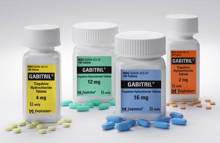 Four white plastic bottles with white caps arranged in a row. Each bottle has a label that reads "Gabitril" in bold black letters. The label also has the brand name "cephalic" written in smaller black letters below it. The bottles are labeled "12 mg" "16 mg" and "2 mg". The labels also mention that the bottles contain 4 mg of the medication. There are also a few small blue and green pills scattered around the bottles. The background is plain white.