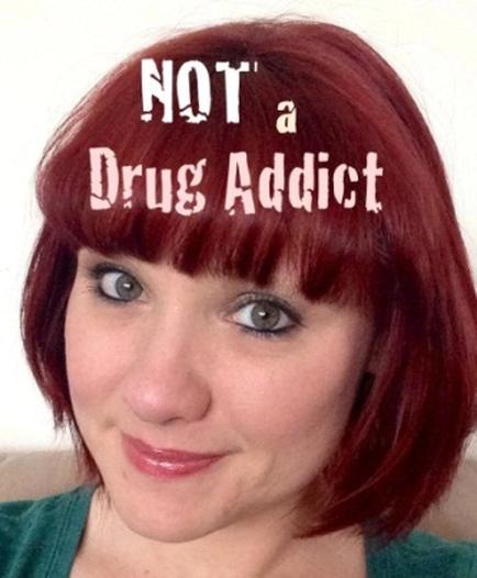 A close-up portrait of a young woman with short red hair. She is smiling and looking directly at the camera. The background is blurred so the focus is on the woman's face. Overlaid on the image is text that reads "NOT a Drug Addict."