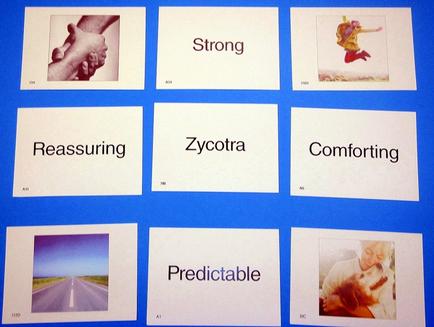 A set of six cards with the words "Strong" "Reassuring" "socotra" "Comforting" and "Predictable" written on them. The cards are arranged in a grid-like pattern on a blue background. The first card on the top left shows a photograph of a hand holding a child's hand. The second card in the top right shows a person jumping in the air with their arms outstretched. The third card is a photo of a road with a blue sky in the background. The fourth card is an image of a woman hugging a dog. The fifth card is another photograph of the same person. The sixth card is the word "measuring" written in black text. All the cards have a white background and the text is written in a bold font.