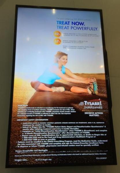 A digital advertisement for Tysabri a fitness company. The advertisement is displayed on a black frame with a white background. The main focus of the advertisement is a photo of a young woman in a blue tank top and black leggings sitting on the ground with her legs stretched out in front of her. She is smiling and appears to be in a yoga pose. The text on the advertisement reads "Treat Now Treat Powerfully." Below the photo there is a list of benefits of the company such as improved safety information increased energy levels and better performance. The company's logo is also visible in the bottom right corner.