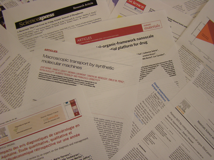 A pile of papers scattered on top of each other. The papers appear to be related to scientific research articles as indicated by the title "Science Express" at the top left corner. The papers are of different sizes and colors with some being white some being red and some being orange. Some of the papers have text written in black while others are white. The text on the papers is in French and appears to be discussing the topic of macroscopic transport by synthetic molecular machines. There is also a red banner at the bottom right corner of the image that reads "Articles - an organic-framework nanoscale - a platform for drug". The papers are likely related to the research articles mentioned in the article.