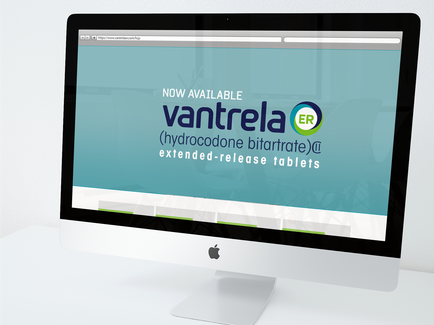 A photograph of a computer monitor displaying a website design for a company called cantrell ER. The website has a blue background with white text that reads "Now Available" and "Hydrocodone nitrate (extended-release tablets)". The company's logo is also visible on the top right corner of the screen. The monitor is placed on a white desk with a white background.