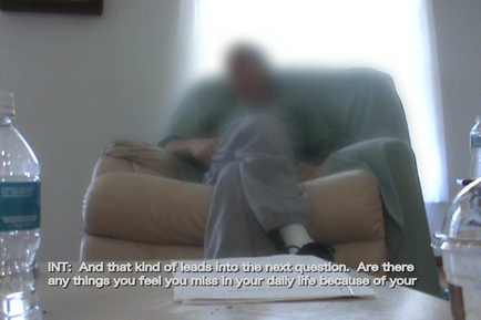 A person sitting on a beige armchair with their head resting on the armrest. The person is wearing a green shirt and grey pants. The background is blurred but it appears to be a living room with a window and a painting hanging on the wall. There are two water bottles on the table in front of the person. The text on the image reads "INT: And that kind of leads into the next question. Are there any things you feel you miss in your daily life because of your life?"