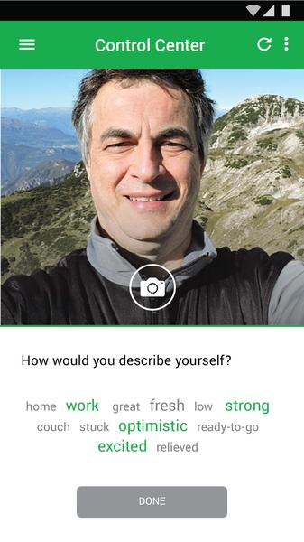 A screenshot of a mobile phone screen with a photo of a man taking a selfish. The man is smiling and looking directly at the camera. He is wearing a black jacket and has short grey hair. The background of the photo is a beautiful landscape of mountains and a clear blue sky. At the top of the screen there is a green button that says "Control Center". Below the button there are two options - "How would you describe yourself?" and "home work great fresh low strong couch stuck optimistic ready-to-go excited relieved".