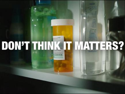 A shelf with various medical supplies on it. On the left side of the shelf there is a green plastic bottle with a blue cap and a white label. Next to it there are two clear plastic bottles with white labels. In the center of the image on the right side is an orange prescription bottle with yellow pills spilling out of it. The label on the bottle reads "Don't think it matters?"