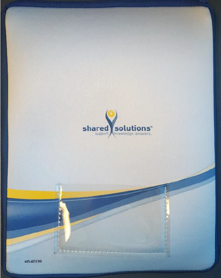 Of a blue folder with a white cover. The folder has a blue border and a yellow stripe running horizontally across the front. On the cover there is a logo of the company "shared solutions" in blue and yellow colors. The logo is a stylized letter "S" with the company's name written in a modern sans-serif font. There is also a small white tag attached to the cover with a clear plastic clip. The background of the cover is white.