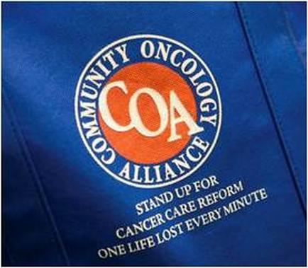 A close-up of a blue fabric with the logo of the Community Oncology Alliance (COA) on it. The logo is circular in shape and has an orange circle in the center with the letters "COA" written in white. Around the circle there is a white text that reads "Stand up for cancer care reform. One life lost every minute." The text is written in a bold sans-serif font and is centered on the fabric. The background of the image is blurred making the logo stand out.