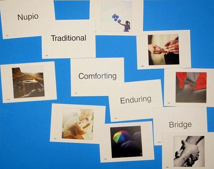 A collection of nine square cards arranged in a grid-like pattern on a blue background. Each card has a different word written on it in white text. The word "Nupio" is written in the center of each card. The first card has the word "Traditional" written in bold letters at the top followed by "Traditional" "Comforting" "Enduring" "Bridge" and "Bridge". Below that there are nine smaller cards with images of different types of people including a person holding hands a person playing with a ball and a person sitting on a couch. The cards appear to be related to the concept of traditional and enduring. On the left side of the image there is a black and white photograph of a person lying on a bed with their head resting on a pillow. On the right side it is a close-up of a hand holding a piece of paper with the words "Bridge" written above it. The background is a solid blue color.