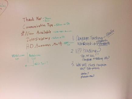 A whiteboard with a list of thank you notes written on it. The notes are written in black marker and are arranged in a neat and organized manner. The list is titled "Thank You - Share Communication Tips - Follow on FB". The list includes: 1. Now Available 2. Campaign Tracking - Headline 3. NPP tracking 4. Who will check campaign data? 5. How will campaign data be tracked? 6. How do you check campaign metrics? There are also two bullet points on the list one for HD Awareness Month and the other for HD awareness month. The first bullet point reads "HDM.com List". The second bullet point says "Watch Back?" At the top left corner of the image there is a red heart with the words "Thank you" written in it.