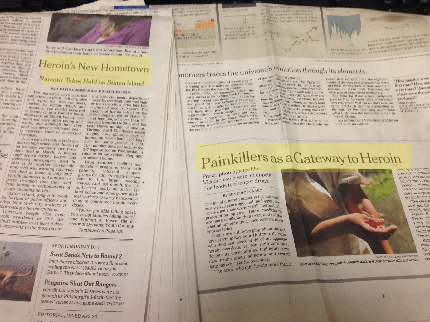 Two pages of a newspaper. The first page is titled "Heroin's New Hometown" and has a headline that reads "Painkillers as a Gateway to Heroin". The second page has an image of a person's hand holding a piece of paper with the headline "Painkillers as Gateway to Heroin" written on it. The background of the page is white and there is a black keyboard visible in the top right corner. The newspaper appears to be old and worn with some creases and wrinkles on the pages.