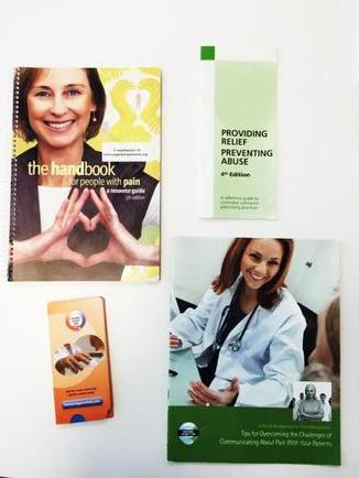 Three books and a small booklet on a white surface. The books are arranged in a triangular formation with the first book on the left the second book in the middle and the third book at the bottom. All three books have a green cover with a photo of a woman in a white lab coat and a stethoscope around her neck. The title of the books is "Providing Patient Care" and the subtitle reads "The Handbook". The booklet has a yellow cover with an image of a smiling woman's face and hands. The booklet also has a blue cover with the title "The handbook" and a picture of a hand holding a book.