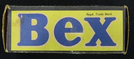 A photograph of a cardboard box with the word "Bex" written in blue capital letters on a yellow background. The box appears to be old and worn with some scratches and scuff marks on the edges. The word "read. Trade Mark" is written in smaller letters below the word. The top of the box has a label that reads "BEX" in blue letters. The background is black making the blue letters stand out.