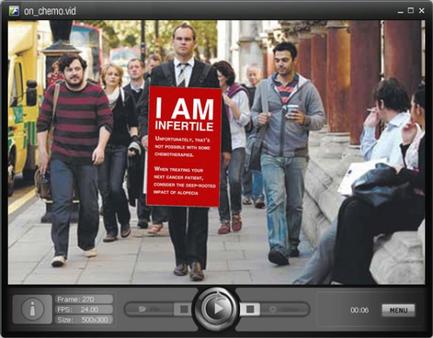 A group of people walking on a street. In the center of the image there is a man holding a red sign that reads "I am infertile". He is wearing a suit and tie and appears to be walking confidently. Behind him there are several other people walking some of whom are carrying bags. On the right side of the screen there seems to be a man sitting on a bench looking at the camera. The background shows a busy street with buildings and a bus.