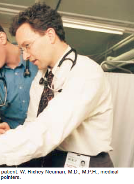 A man wearing a white lab coat and a stethoscope around his neck. He appears to be a medical professional as he is wearing glasses and has a name tag that reads "patient. W. richer newman M.D. M.P.H. medical pointers." He is standing in a room with a white curtain in the background and another person wearing a blue shirt is standing behind him. The man is looking down at something on his desk possibly a medical chart or a clipboard.
