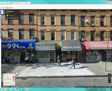 A street view of a two-story brick building on a corner of a street. The building has multiple windows and a blue awning with the words "99¢ Plus Pharmacy" and "Medical Office" written on it. There are several other shops on the corner of the street including a pharmacy and a convenience store. A couple of people can be seen walking on the sidewalk in front of the pharmacy. The street is empty with no cars or people visible. The image appears to be taken from a Google Street View perspective.