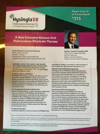 A photograph of a brochure or pamphlet with a pink and green color scheme. The brochure is titled "Hygiene ER #315" and has a photo of a man in a suit and tie on the top left corner. On the right side of the brochure there is a list of information about the product including the product name description and price. The text is written in black font and is divided into two columns. The left column has the Hygiene ER logo and the product's name in white font. The right column has a brief description of the product and its benefits. The brochure appears to be lying on a wooden surface possibly a table or countertype.