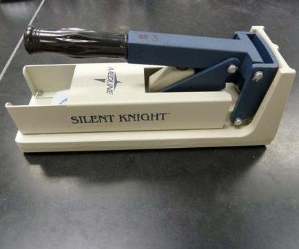 A Silent Knight stapler which is a type of stapling machine used for cutting and shaping materials. It has a white base with the brand name "Silent Knight" written on it in black letters. The top of the base has a blue handle with a black nozzle which can be used to cut through the material. The handle is attached to the base with screws. The base also has a small opening on the right side which allows the user to insert the material into the base. The staplers are placed on a black surface.