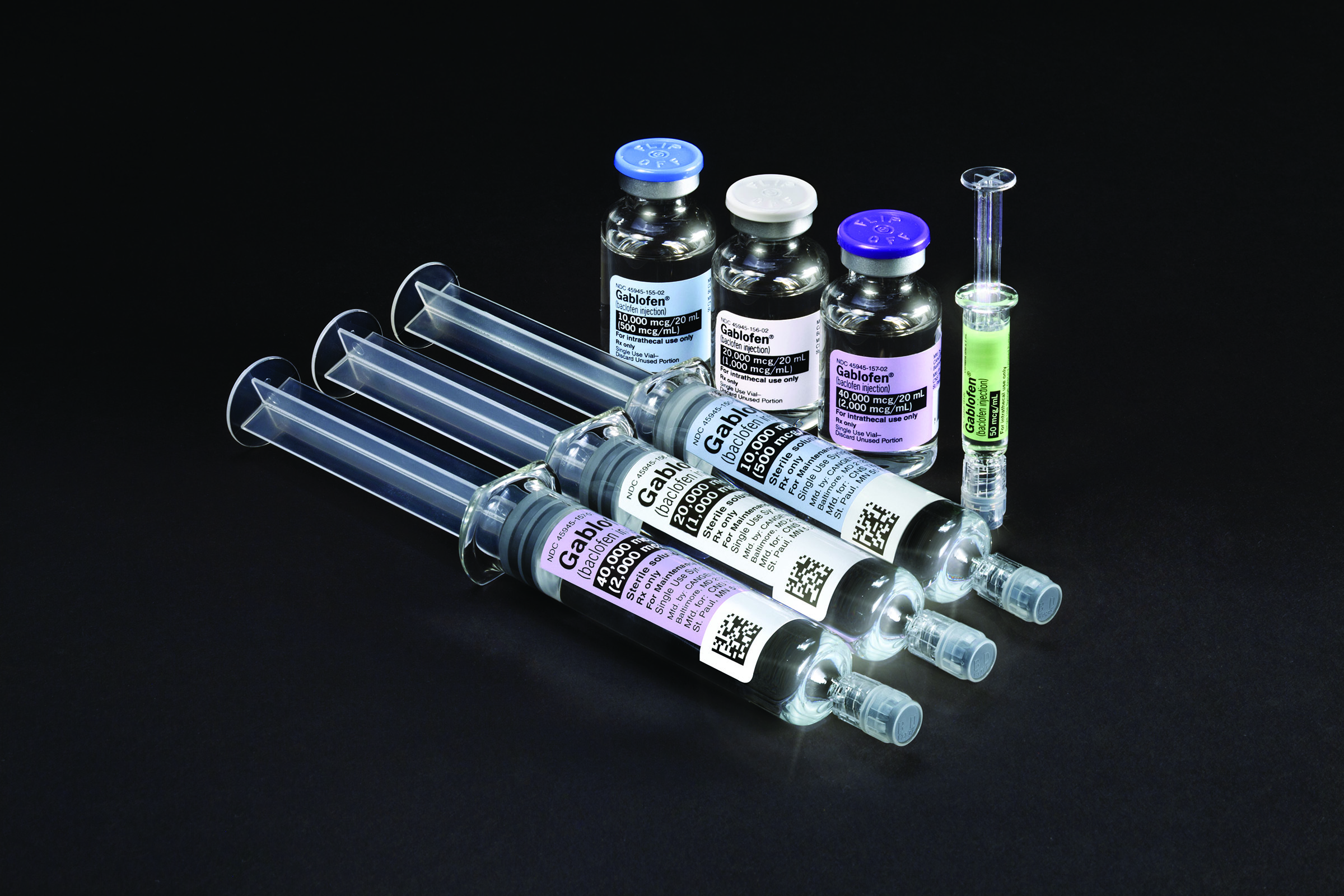A three pairs of syringes and vials as well as an additional smaller syringe. All the syringes are made of clear glass or plastic and have a cylindrical shape. Each pair has a matching color scheme in blue white or purple. The smaller syringe has a green label. Each syringe and vial is labeled with "Gablofen" and each represents a dose between 50mcg and 40000 mcg. The background is black making the colors of the syringe and vials stand out.