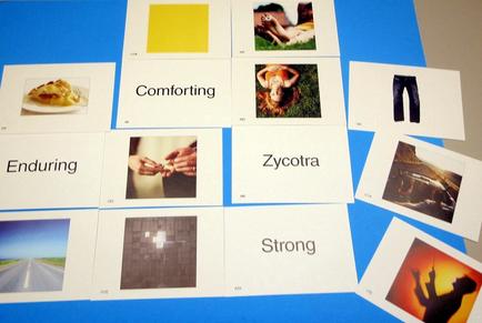 A collage of multiple photographs arranged in a grid-like pattern on a blue background. There are nine photographs in total arranged in two rows and three columns. The first row of photographs on the top left shows a plate of food with a fork and knife the second row shows a person lying on the ground the third row shows two people holding hands and the fourth row shows three people walking on a road with a blue sky in the background. In the center of each photograph there is a yellow square with the word "Comforting" written on it. Below the square there are two smaller photographs of a person's hand holding a piece of paper with the words "Enduring" and "socotra" written in black text. On the right side of the image there appears to be a pair of jeans and on the bottom right corner there seems to be another photograph of a man walking on the street with his arms outstretched. The word "Strong" is written in white text above the photographs.