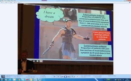 A screenshot of a presentation slide on a computer screen. The slide has a picture of a man dressed as a Roman soldier holding a sword and wearing a helmet and armor. He is standing in front of a blue background with a speech bubble above his head that reads "I have a dream". Below the speech bubble there is text that explains that the presentation is about the future primary endpoint of a patient who has been diagnosed with cancer. On the right side of the slide there are three bullet points that explain the current primary endpoint and how it affects the patient's health. The first bullet point explains that from group means (average patient) to individual patients the second bullet point mentions that the patient has a free and free post-bothers syndrome and the third bullet point discusses the treatment of the disease. In the bottom left corner of the image there appears to be a man sitting at a desk with a microphone in his hand.